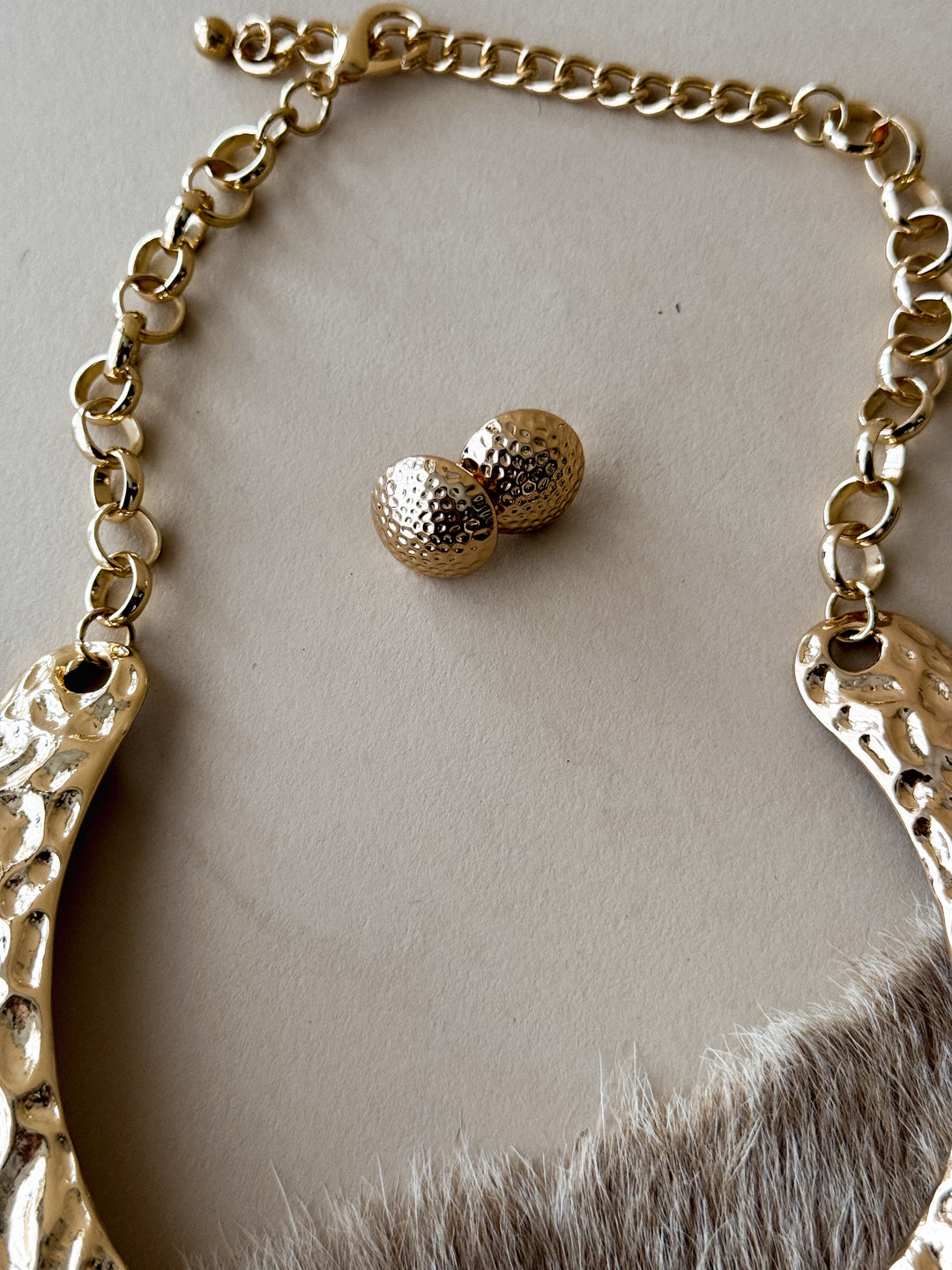 Gold hammered earrings styled on cowhide background