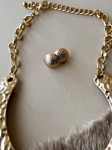 Gold hammered earrings styled on cowhide background