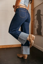 High rise western cuff jeans with wide rolled hems and tan cowboy boots in a boho setting
