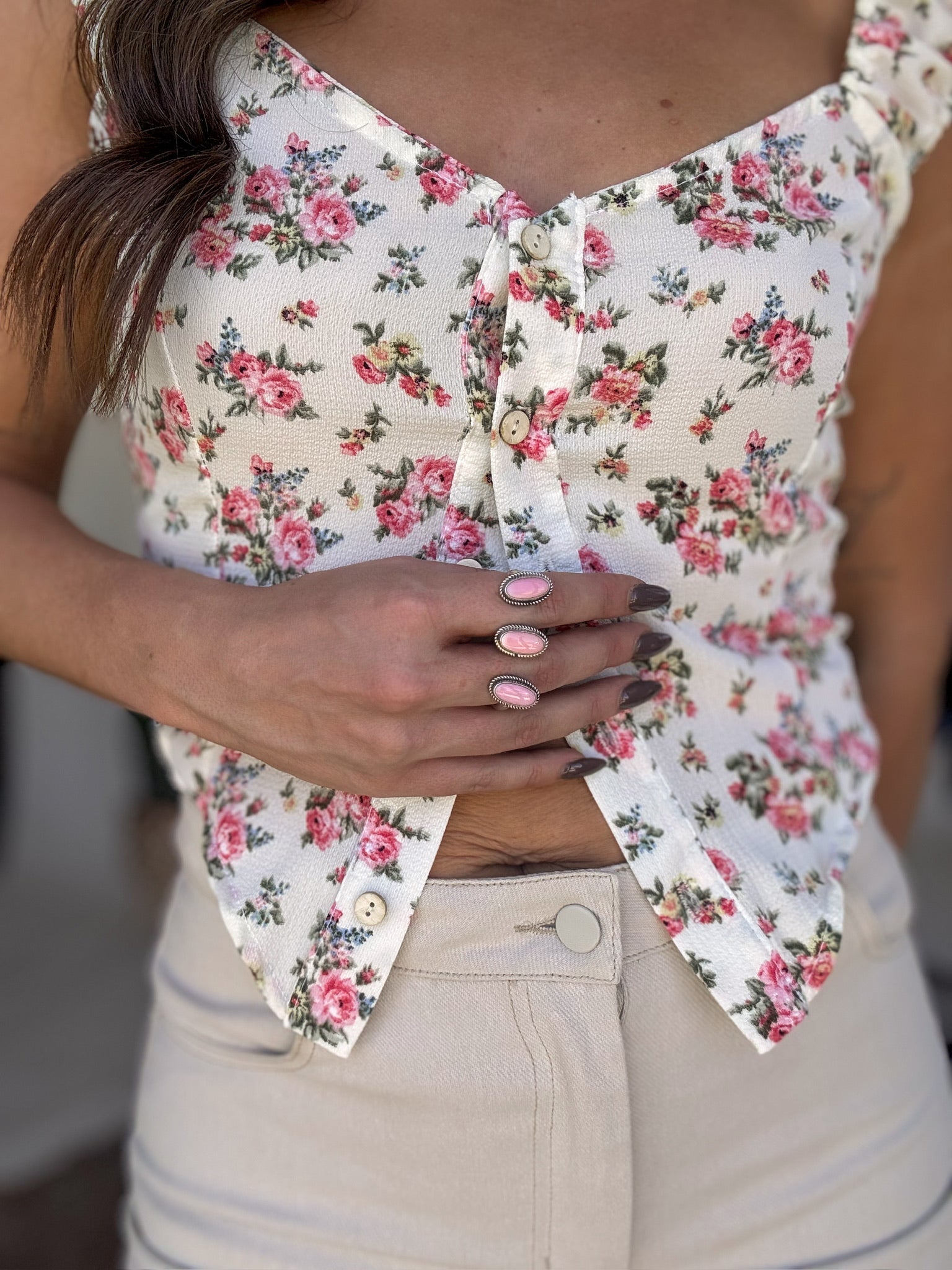 Woman wearing a floral button front crop top with ruffle straps and beige high-waisted jeans